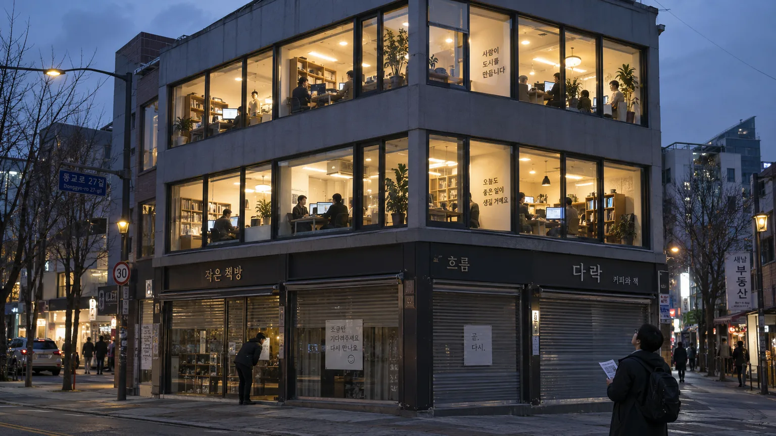 street with ground floor shops showing paper signs on the glass and fully lit occupied upper floor offices